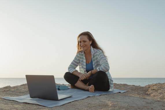 Femme sereine recevant un soin énergétique à distance en visio au bord de la mer