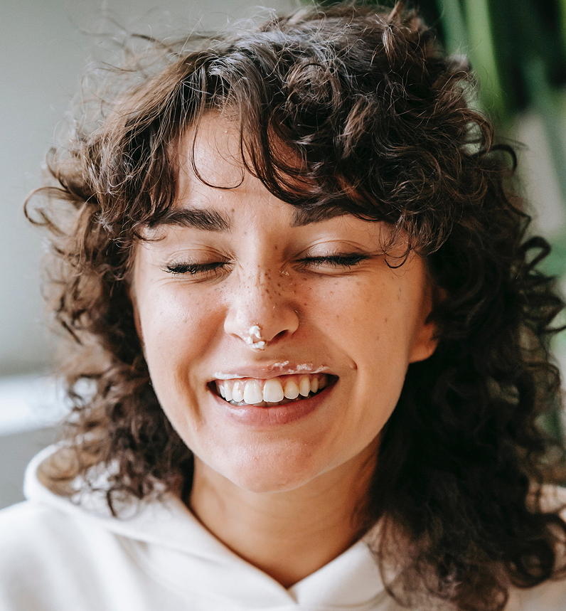 Femme souriante et détendue riant d'elle-même – Retrouver équilibre et légèreté énergéticienne Perpignan